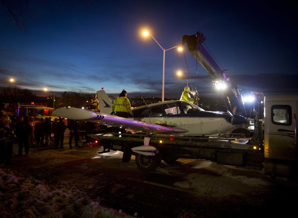 A single engine plane is loaded onto a flat bed truck after landing on Major Deegan Expressway in the Bronx borough of New York