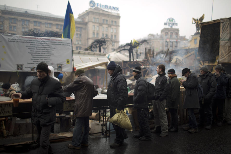 People line up as they wait a ration of soup made by anti-Yanukovych protesters in Kiev's Independence Square, the epicenter of the country's current unrest, Ukraine, Sunday, March 2, 2014. A convoy of hundreds of Russian troops is heading toward the regional capital, Simferopol on the Crimean peninsula in Ukraine today. On the road from Sevastopol, the Crimean port where Russia maintains a naval base, AP journalists saw 12 military trucks. Russian troops took over the strategic Black Sea peninsula yesterday and are ignoring international protests. (AP Photo/Emilio Morenatti)