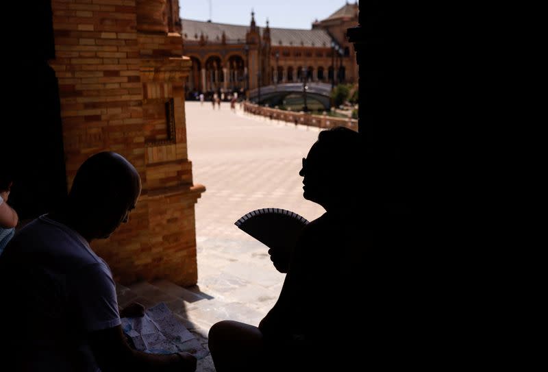 Varias personas se protegen del calor a la sombra en Sevilla, España.