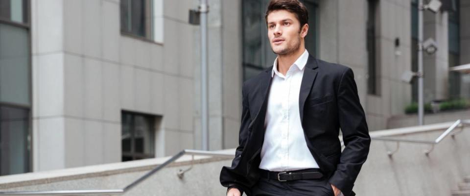 Confident young businessman in suit walking on the street