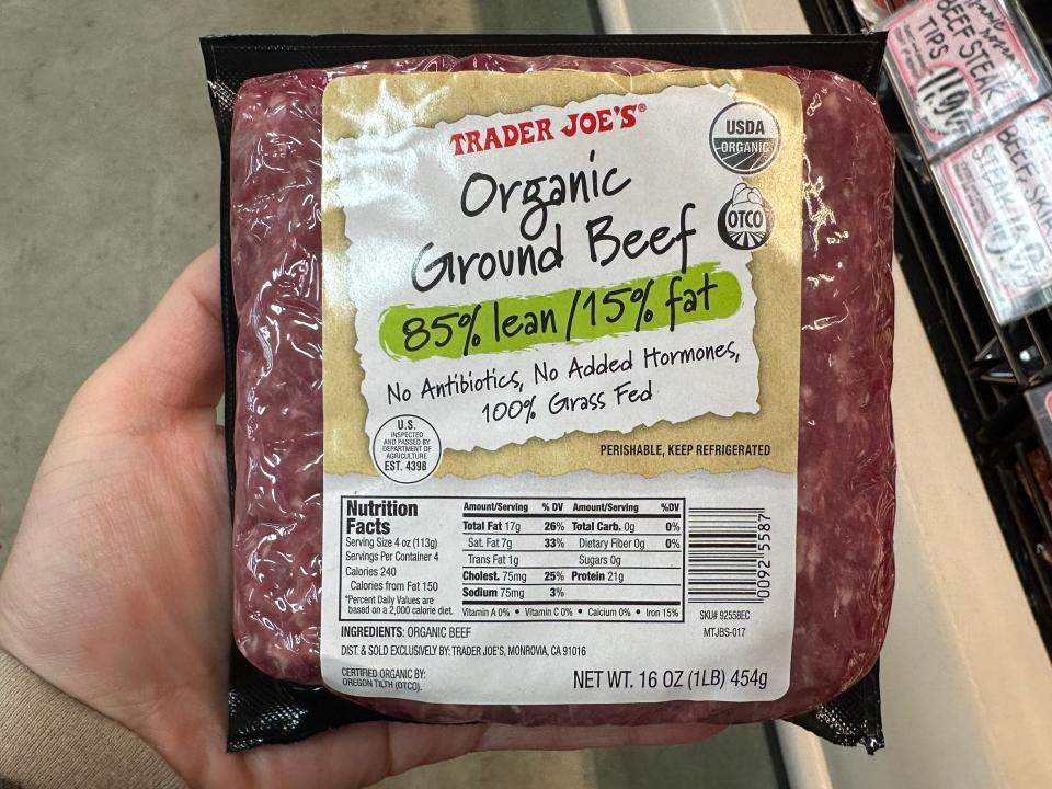 hand holding up a package of trader joe's organic ground beef