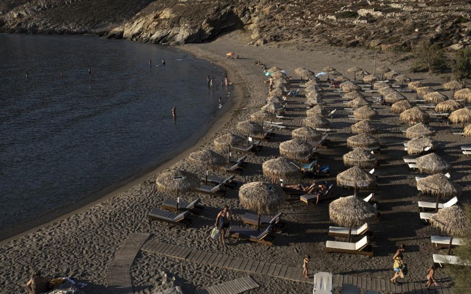 Tourists sit under beach umbrellas at Marmari beach, Mani peninsula, Peloponnese region, Greece on Thursday - Konstantinos Tsakalidis/Bloomberg