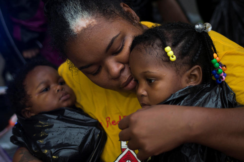 Laquanta Edwards holds her 1-year-old daughter Ladaja, right, and 9-month-old son LaDarius after they arrived to high ground by boat in east Houston.