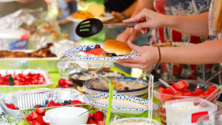 person plating food at potluck barbecue