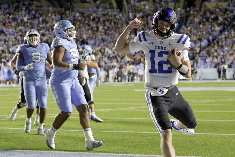 Duke quarterback Grayson Loftis (12) celebrates as he runs past North Carolina defensive linemen Myles Murphy (8) and lineman Kevin Hester Jr. (98) for a touchdown during the first half of an NCAA college football game Saturday, Nov. 11, 2023, in Chapel Hill, N.C. (AP Photo/Chris Seward)