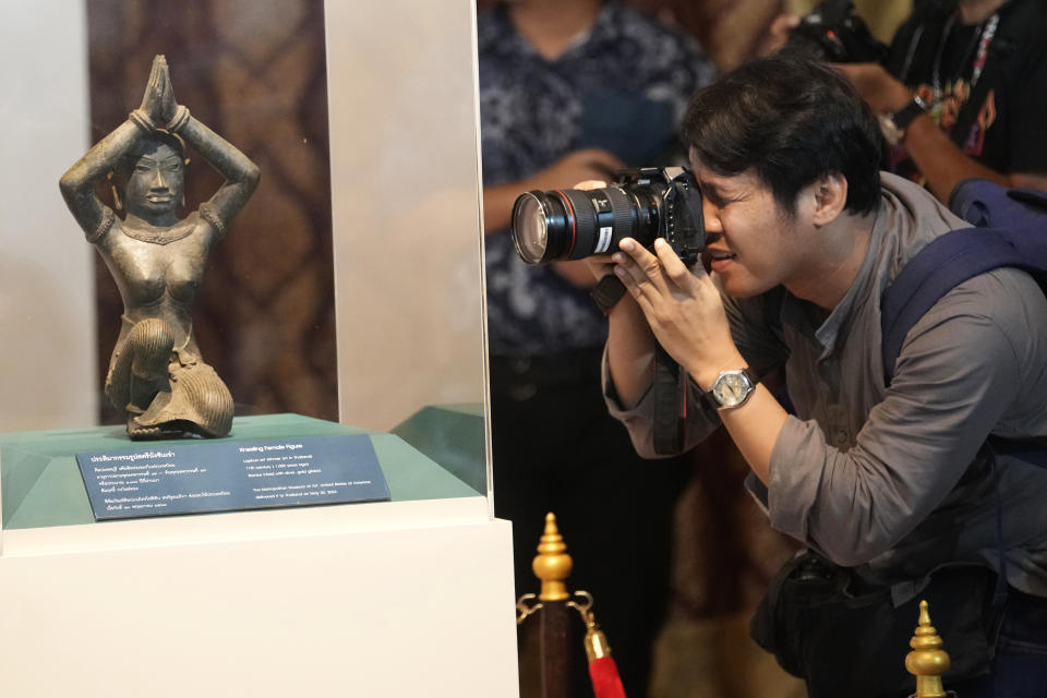 Thai photographer takes a picture of the ancient bronze kneeling woman sculpture during a repatriation ceremony at National Museum in Bangkok, Thailand, Tuesday, May 21, 2024. Thailand's National Museum hosted a welcome-home ceremony Tuesday for two ancient statues that were illegally trafficked from Thailand by a British collector of antiquities and were returned from the collection of New York’s Metropolitan Museum of Art. (AP Photo/Sakchai Lalit)