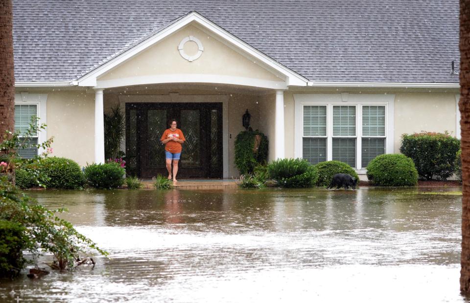 FILE - A woman watches her dog play in their flooded yard on Windward Island on Savannah’s south side on Monday, Sept. 11, 2017, after Hurricane Irma went into Georgia. Irma brought FEMA personnel to the Island, and many coastal Georgia residents pursued extra flood-safety measures after the fact to protect houses.