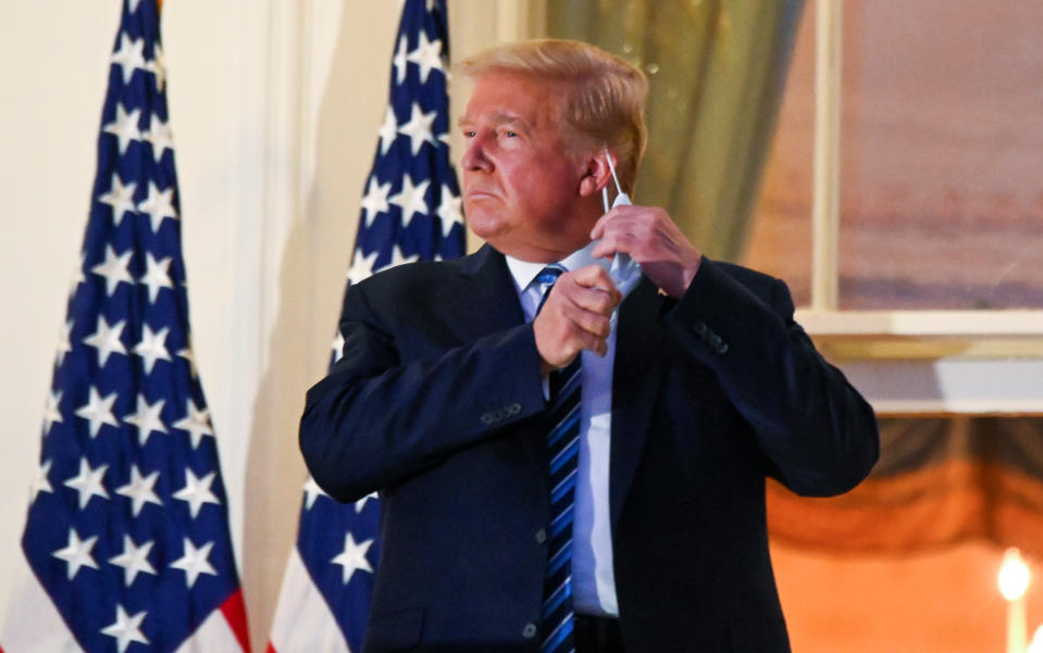 U.S. President Donald Trump pulls off his protective face mask as he poses atop the Truman Balcony of the White House after returning from being hospitalized at Walter Reed Medical Center for coronavirus disease (COVID-19) treatment, in Washington, U.S. October 5, 2020. REUTERS/Erin Scott