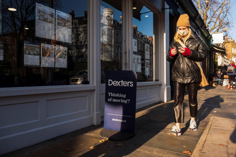 House prices  A person looking at a smartphone walks past a branch of Dexters estate agents in Islington, London, Britain, December 10, 2021. Picture taken December 10, 2021. REUTERS/May James