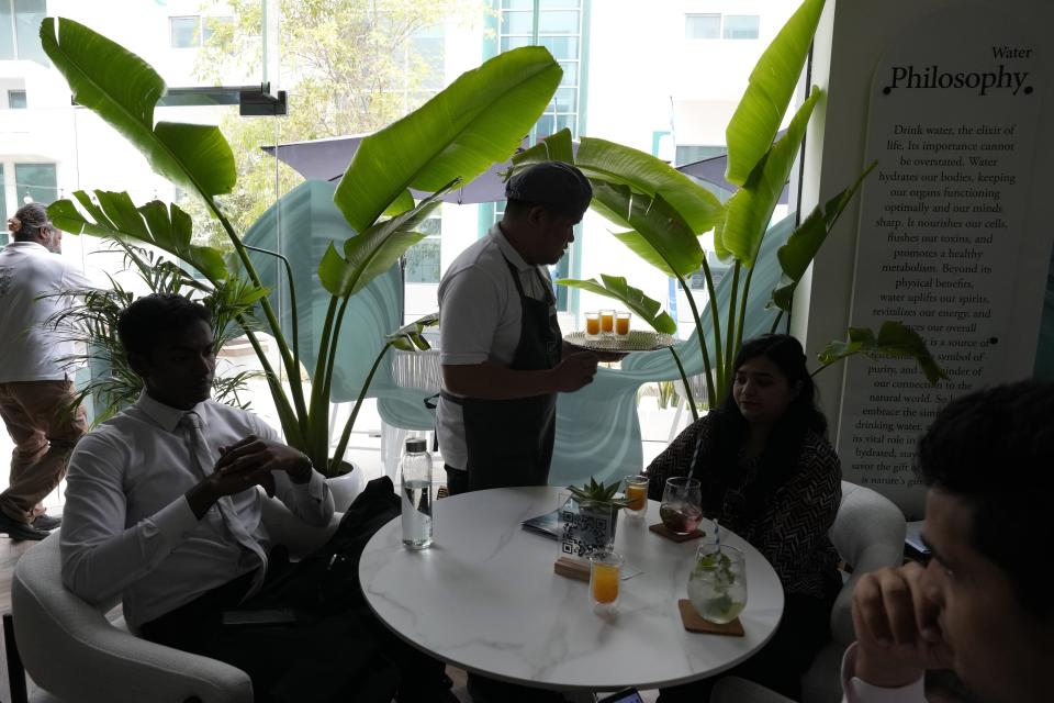 A server presents specially crafted shots to customers at the AQUA Water Bar by LUQEL in Dubai, United Arab Emirates, Tuesday, July 11, 2023. Dubai's gourmet water bar joins a growing list of unique businesses that have sprouted out of the uninterrupted stretches of windblown sand dunes turned into a bustling desert metropolis, complete with the world's tallest building, cavernous malls, and palm-shaped man-made islands. (AP Photo/Kamran Jebreili)