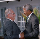 FILE - Former U.S. Secretary of State Henry Kissinger, left, and African National Congress (ANC) president Nelson Mandela shake hands during their meeting in Johannesburg, South Africa, on April 13, 1994. The South African government announced Friday Jan. 19, 2024 that it plans to challenge an auction of artifacts which belonged to Mandela, set to take place in New York next month. (AP Photo/John Parkin, File)