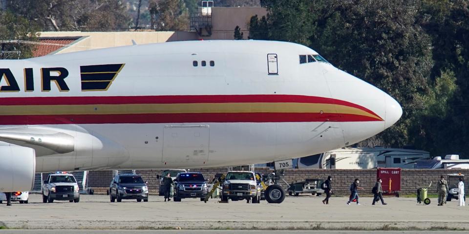 Passengers walk past personnel in protective clothing after arriving on an aircraft, chartered by the U.S. State Department to evacuate government employees and other Americans from the novel coronavirus threat in the Chinese city of Wuhan, at March Air Reserve Base in Riverside County, California, U.S., January 29, 2020. REUTERS/Mike Blake