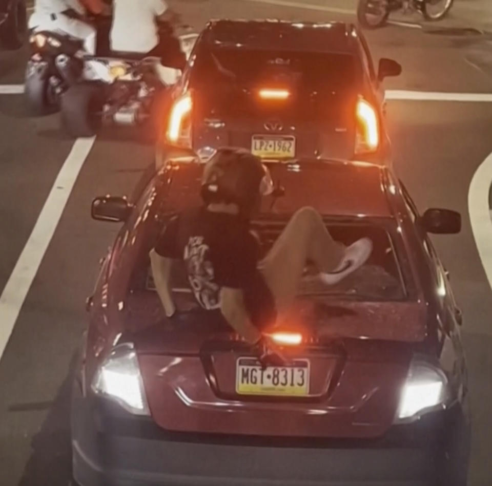 This image provided by George Coloney/@Vortex.hz shows a shows a biker smashing a car’s back window on Sunday, Oct. 1, 2023 in Philadelphia. According to authorities, Cody Heron is accused of being the motorcyclist seen smashing in the back of a woman's car while her two young children were inside near Philadelphia's City Hall and then waving a gun at her after she confronted him has been charged with multiple counts of aggravated assault. (Courtesy of George Coloney/@Vortex.hz via AP)