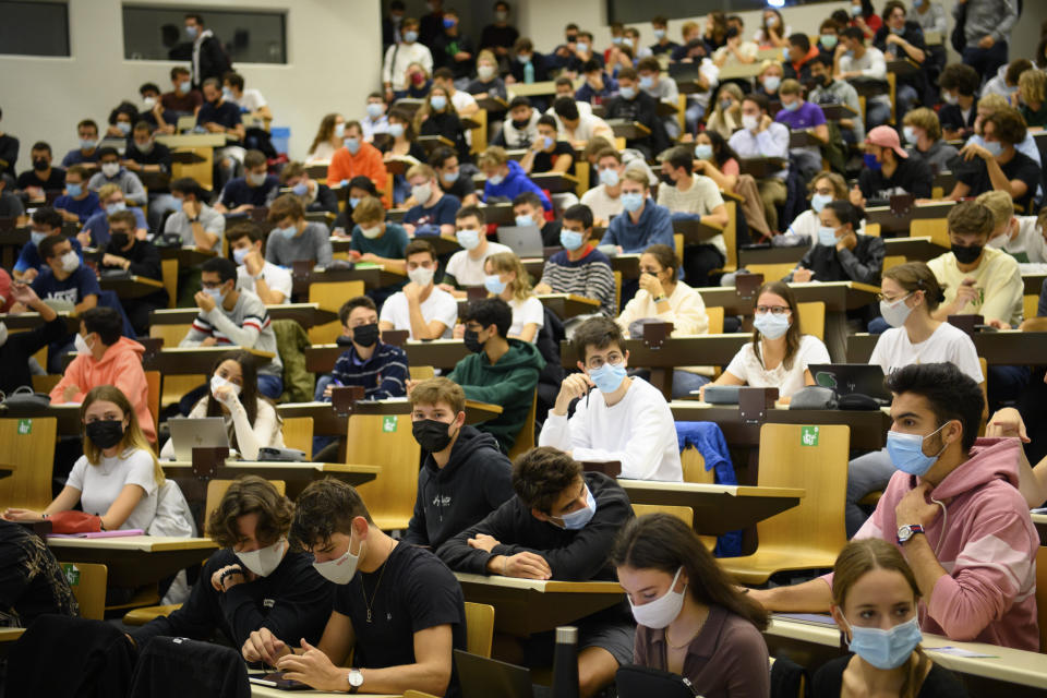 FILE - Students wearing face masks after they have been checked at the entrance of an auditorium for a validated Covid Certificate during a lecture at the Swiss Federal Institute of Technology, in Lausanne, Switzerland, September 21, 2021. Switzerland is facing an exponential rise in coronavirus cases. But its federal government, hasn't responded with new lockdown measures. Experts say that's because the government's anti-COVID policies face a crucial test at the ballot box. On Sunday Nov. 28, 2021, Swiss voters will cast ballots on a ‚COVID-19 law' that has unlocked billions of Swiss francs in aid for workers and businesses hit by the pandemic. (Laurent Gillieron/Keystone via AP, File)