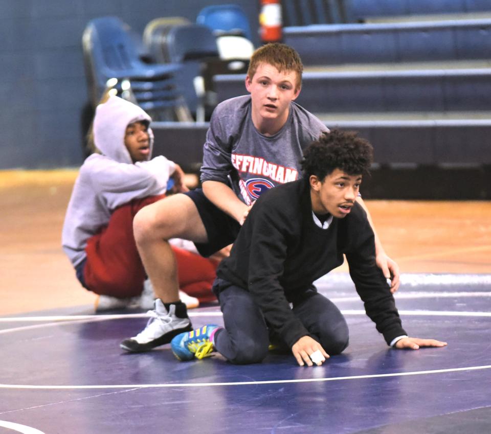 Effingham County High School wrestler Mal Santiago goes through neutral drills with teammates Ian Johnsen (on top) and Akenyon Wallace (at the edge of the mat).