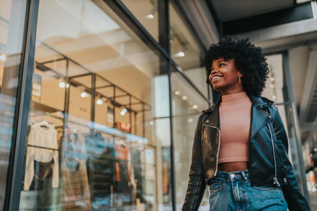 A young woman out shopping in the city. Afro female standing in front of boutique and looking in the shop window