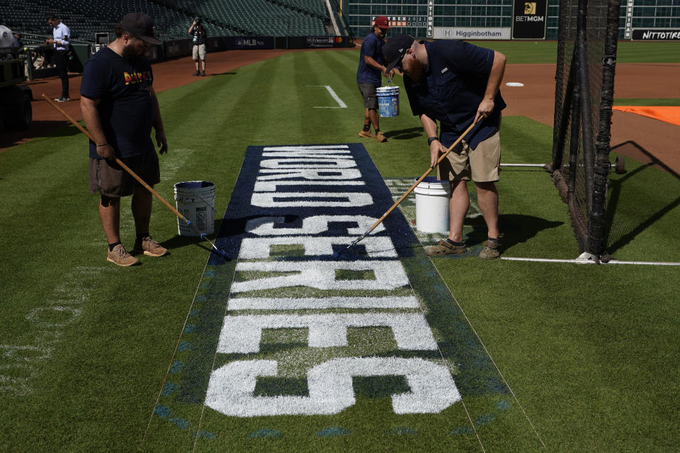 Stadium workers paint the logo on the field Monday, Oct. 25, 2021, in Houston, in preparation for Game 1 of baseball's World Series tomorrow between the Houston Astros and the Atlanta Braves. (AP Photo/David J. Phillip)
