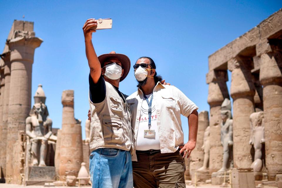 Mask-clad tour guides pose for a selfie at the Temple of Luxor (AFP via Getty Images)