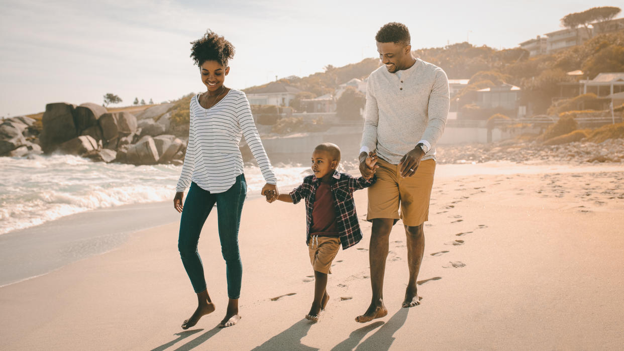 mom and dad walking on beach with son on vacation