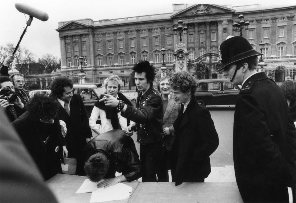 The Sex Pistols with their manager Malcolm McLaren signing a new contract with A&M Records, outside Buckingham Palace in March 1977. The contract was terminated after one week. - Credit: Graham Wood/Evening Standard/Hulton Archive/Getty Images