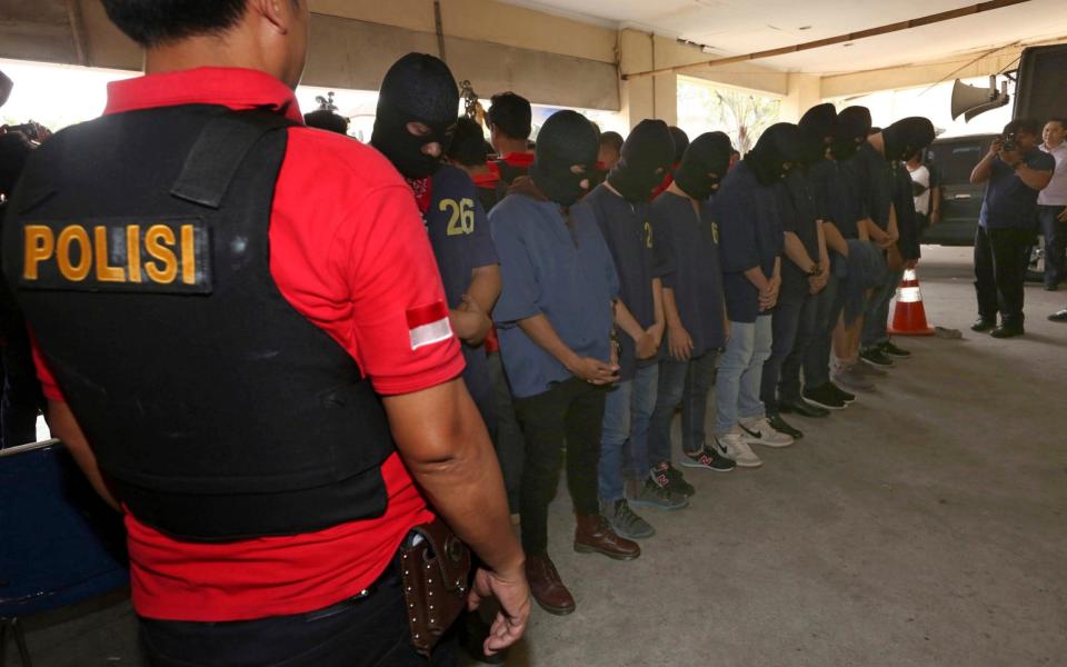 Police officers escort men arrested in a raid on a gay sauna at North Jakarta police headquarters in Jakarta,Indonesia, Monday, May 22 - Credit: Tatan Syuflana/AP