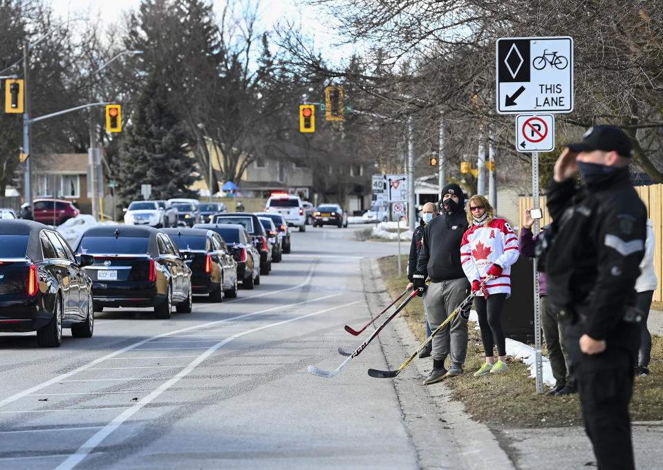 People honor and pay their respects as the funeral procession for Walter Gretzky passes by in Brantford, Ontario, on Saturday, March 6, 2021. Walter Gretzky also know as Canada's hockey dad was 82 years old. (Nathan Denette/The Canadian Press via AP)