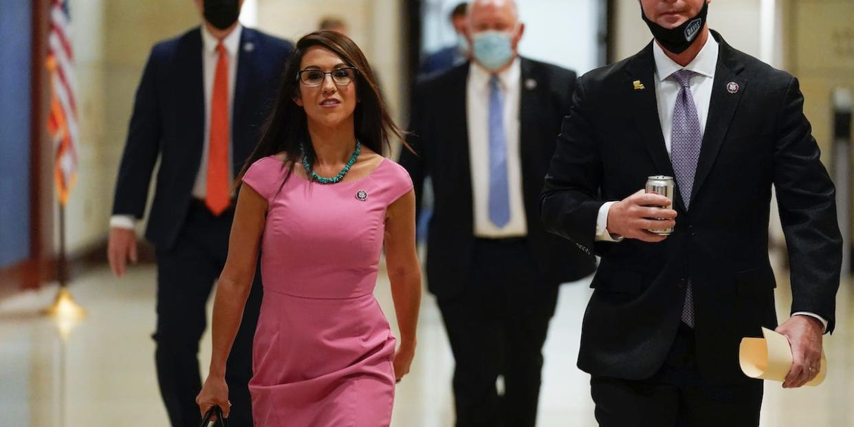 Rep. Lauren Boebert, R-Colo., walking without a face mask, left, and Rep. Rodney Davis, R-Ill., head to a House Republican Conference meeting, Wednesday, April 14, 2021, at the Capitol in Washington.