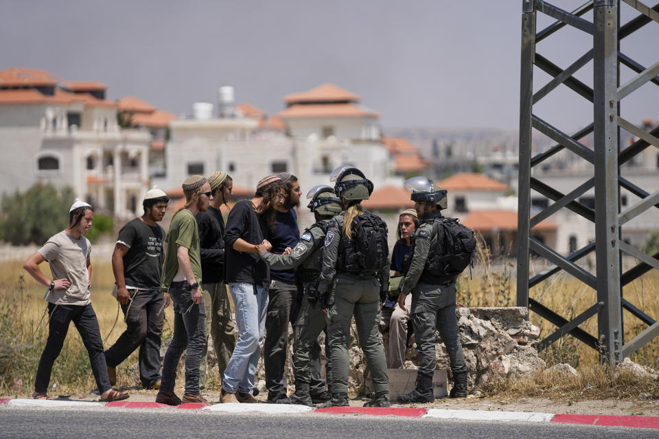 Israeli border police officers stop Jewish settlers from entering the Palestinian West Bank town of Turmus Ayya, Wednesday, June 21, 2023. Israeli settlers set fire to Palestinian cars after four Israelis were killed by Palestinian gunmen in the northern West Bank on Tuesday. (AP Photo/Ohad Zwigenberg)