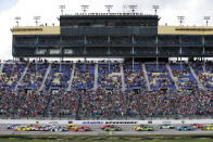 Fans watch from the grandstand as race cars cross the start/finish line at the start of a NASCAR Cup Series auto race at Kansas Speedway in Kansas City, Kan., Sunday, Oct. 24, 2021. (AP Photo/Colin E. Braley)