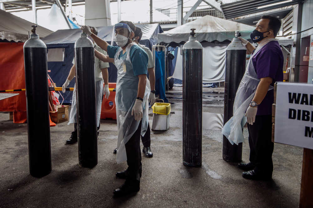 Workers arrange medical oxygen cylinders to be sent to the Covid-19 Low-Risk Quarantine and Treatment Centre (PKRC) at the Malaysia Agriculture Expo Park (MAEPS) at Hospital Serdang July 26, 2021. — Picture by Shafwan Zaidon