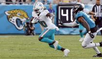 Miami Dolphins wide receiver Tyreek Hill (10) carries the ball as Jacksonville Jaguars safety Andre Cisco (5) pursues in the first quarter of an NFL football preseason game in Jacksonville, Fla., Saturday, Aug. 26, 2023. (Al Diaz/Miami Herald via AP)