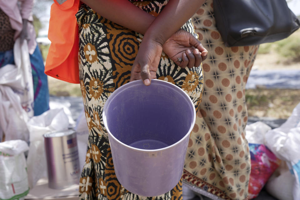 A woman holds an empty bucket while waiting to receive food aid in a queue in Mangwe district in southwestern Zimbabwe, Friday, March, 22, 2024. A new drought has left millions facing hunger in southern Africa as they experience the effects of extreme weather that scientists say is becoming more frequent and more damaging. (AP Photo/Tsvangirayi Mukwazhi)