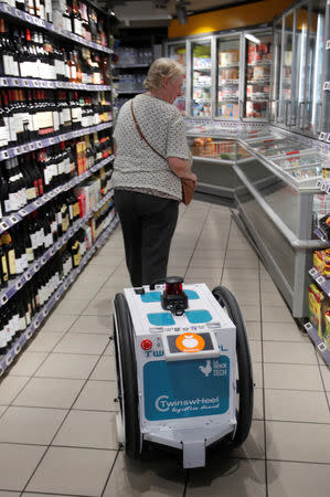 A woman does her shopping at a store using an autonomous robot, shaped and inspired by Star Wars R2D2, in a test for the delivery of groceries by Franprix supermarket chain in the 13th district of Paris, France, April 17, 2019. REUTERS/Charles Platiau