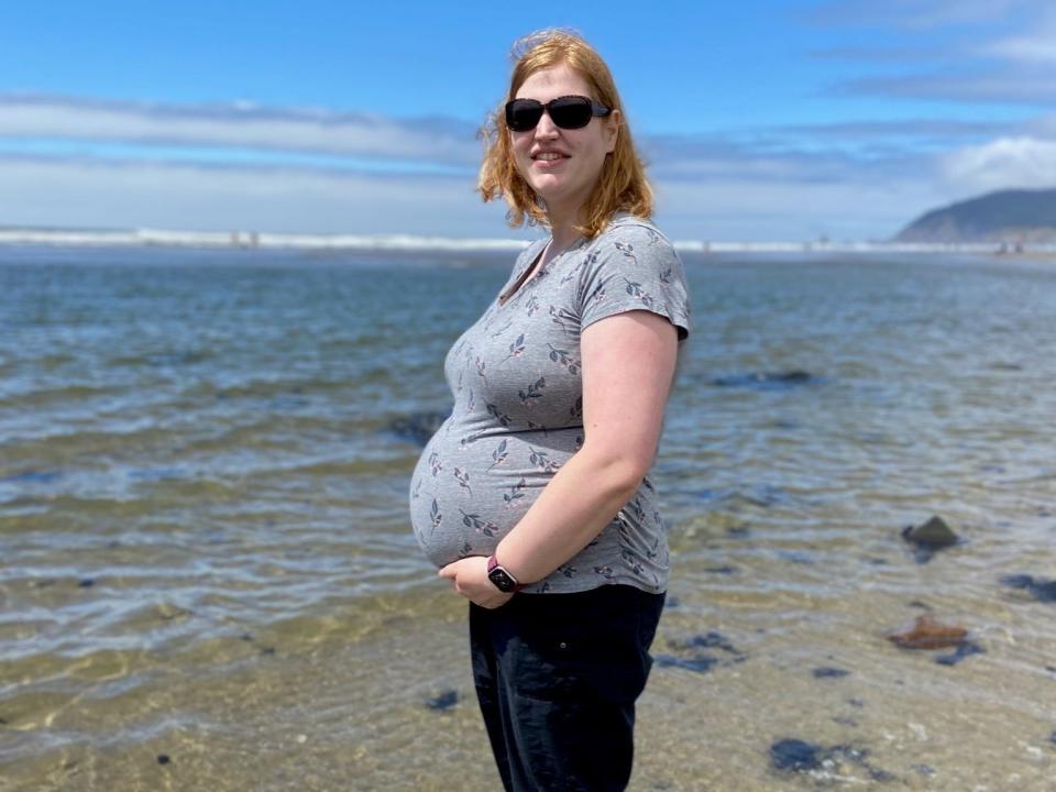 Rachel Ridgeway, pregnant with twins, stands on a beach in 2022
