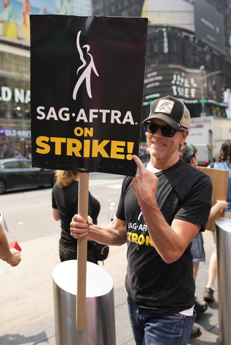 Actor Kevin Bacon carries a sign on a picket line outside Paramount in Times Square on Monday, July 17, 2023, in New York. The actors strike comes more than two months after screenwriters began striking in their bid to get better pay and working conditions and have clear guidelines around the use of AI in film and television productions. (Photo by Charles Sykes/Invision/AP)