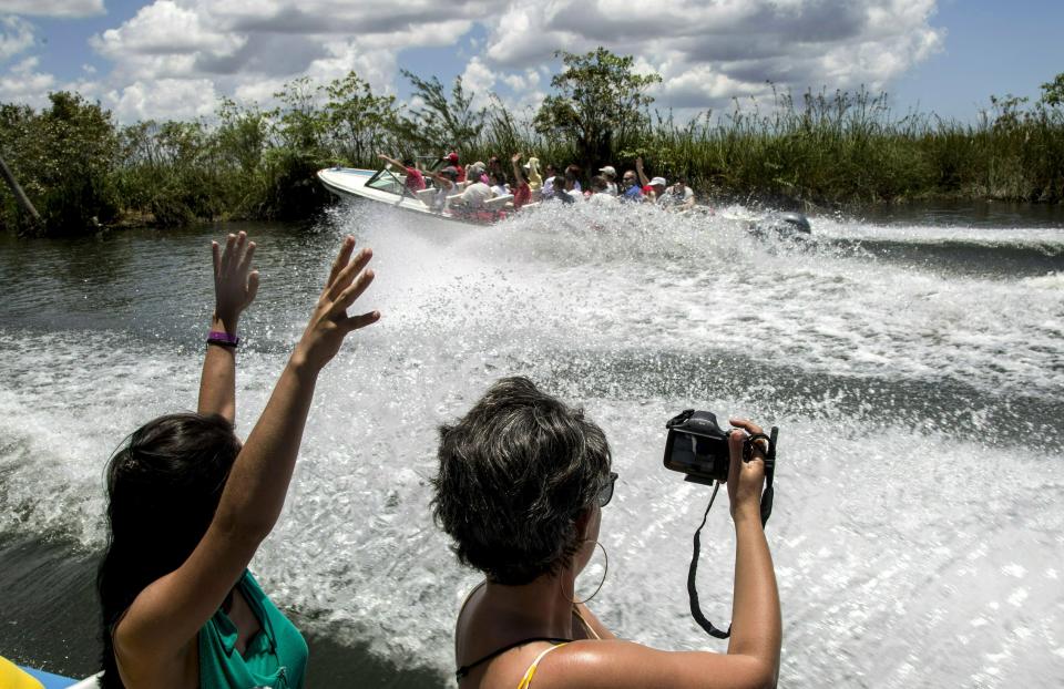 In this May 13, 2019 photo, tourists take photos while being transported by boat to the Laguna del Tesoro, in the Zapata Peninsula, Matanzas, Cuba. The U.S. has prohibited Americans from patronizing a series of hotels and other facilities run by the military conglomerate that controls many of the most important sectors of the Cuban economy. (AP Photo/Ismael Francisco)