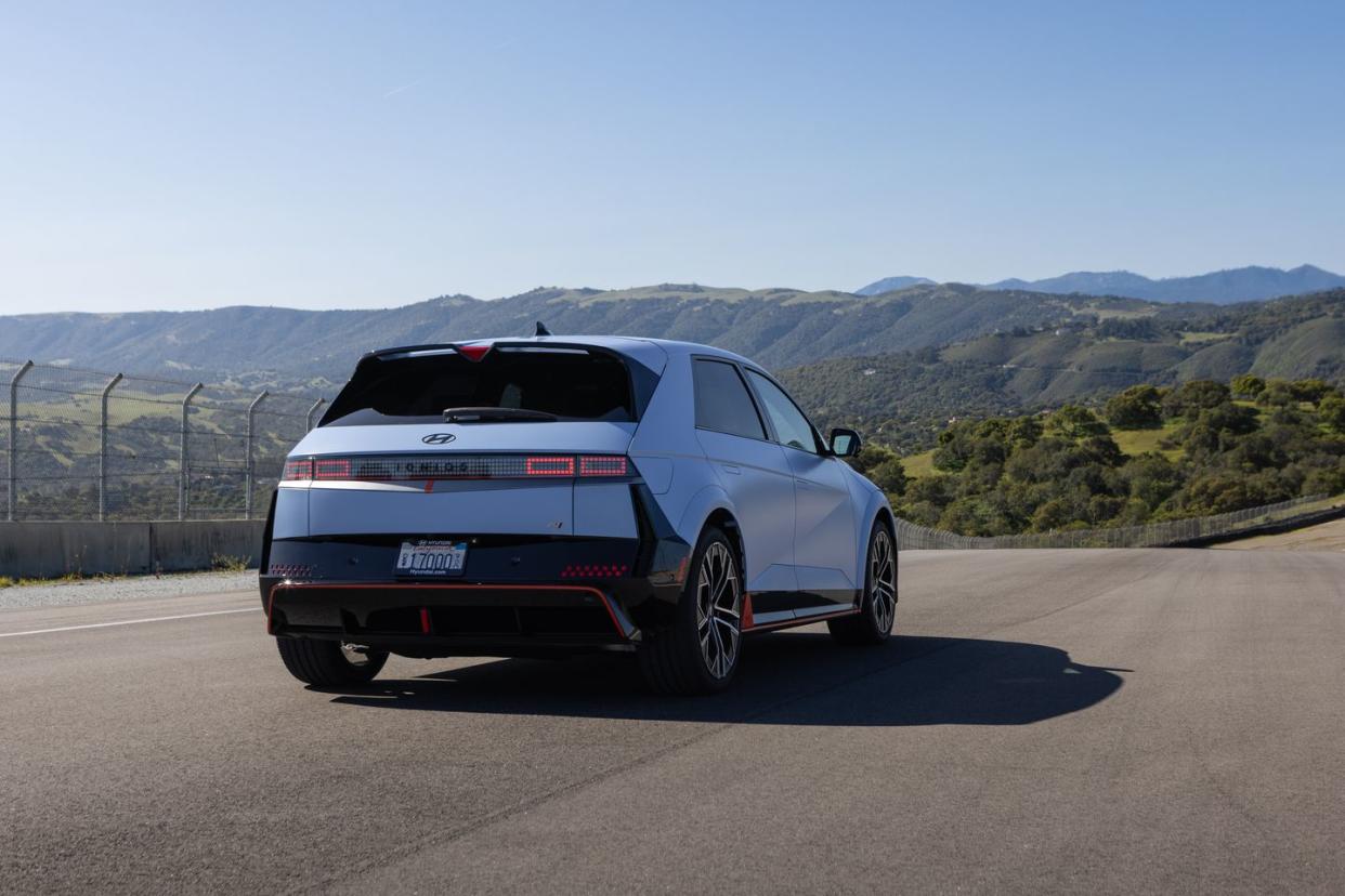 a white car with red stripes on a road with hills in the background