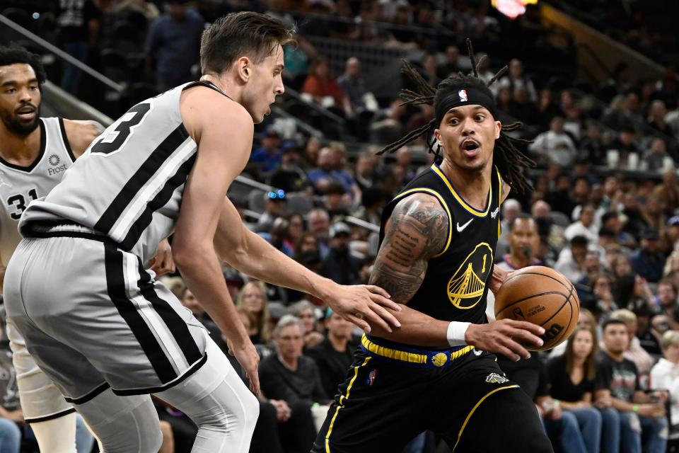 Golden State Warriors' Damion Lee (1) drives against San Antonio Spurs' Zach Collins during the first half of an NBA basketball game on Saturday, April 9, 2022, in San Antonio. (AP Photo/Darren Abate)