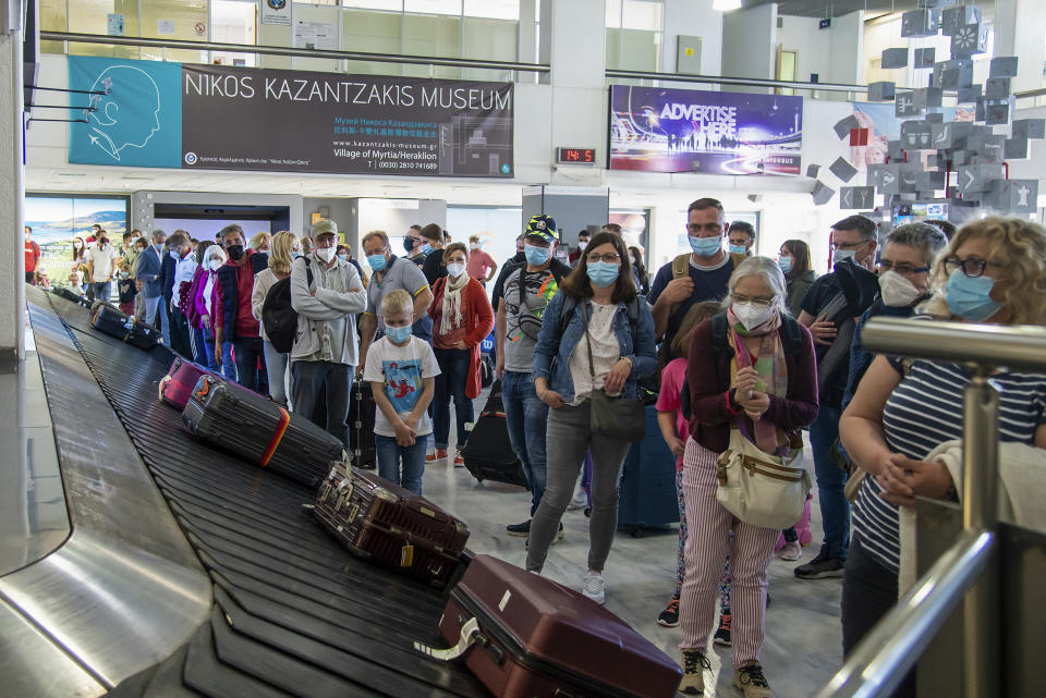 FILE - In this May 14, 2021, file photo, passengers from Hanover wait to pick their luggage at Nikos Kazantzakis International Airport in Heraklion, on the island of Crete, Greece. Coronavirus infections, hospitalizations and deaths are plummeting across much of Europe. Vaccination rates are accelerating, and with them, the promise of summer vacations. (AP Photo/Harry Nakos, File)