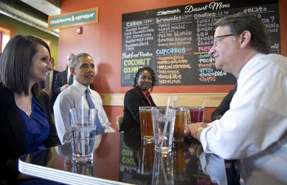 President Barack Obama sitting between Mira Friedlander, a 22 year old senior at the University of Michigan, left, and Aisha Turner, 36, a mother of three who has worked for nearly two decades as a server, and Rep. Gary Peters, D-Mich., right, have lunch at Zingerman's Deli in Ann Arbor, Mich., Wednesday, April 2, 2014, before the president was to speak at the University of Michigan about his proposal to raise the national minimum wage. (AP Photo/Carolyn Kaster)