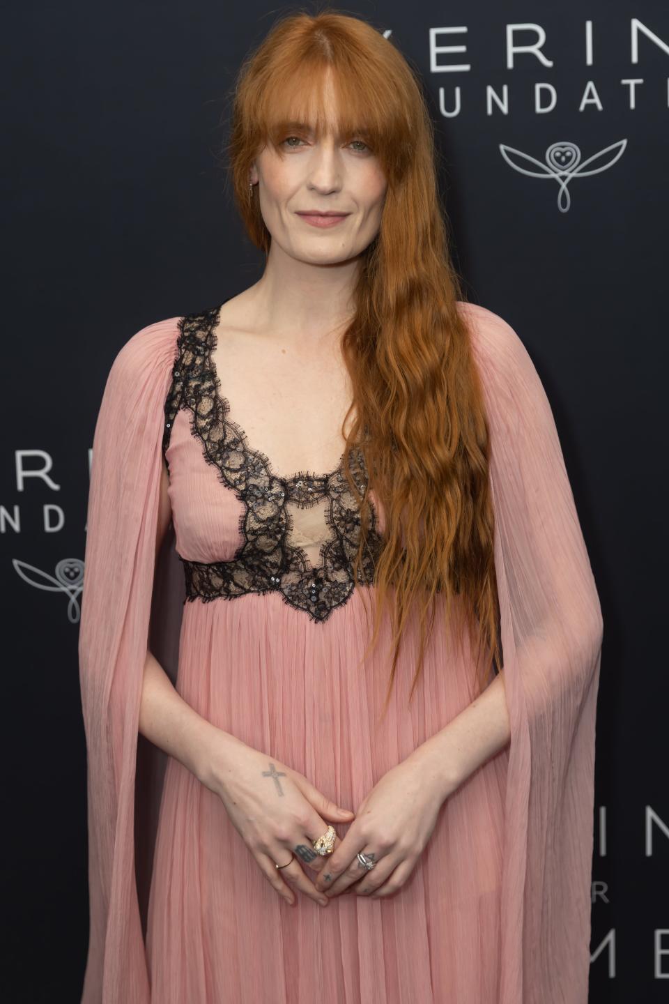 Florence Welch in a dress with lace details smiles on the red carpet