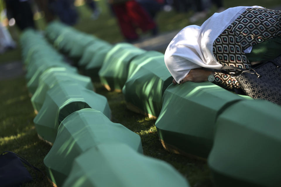 A Bosnian muslim woman mourns next to the coffin containing remains of her family member who is among 50 newly identified victims of Srebrenica Genocide in Potocari, Monday, July 11, 2022. Thousands converge on the eastern Bosnian town of Srebrenica to commemorate the 27th anniversary on Monday of Europe's only acknowledged genocide since World War II. (AP Photo/Armin Durgut)