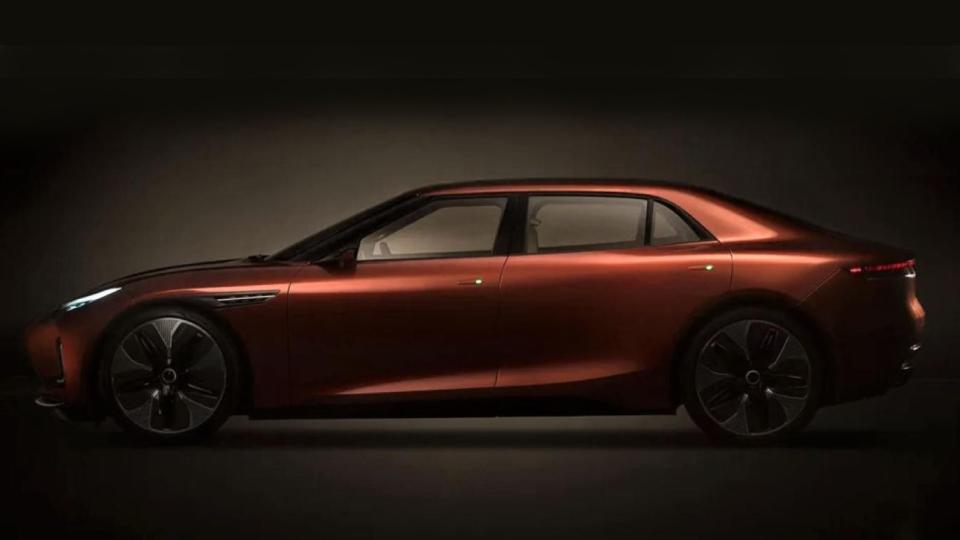 a dark copper four door sedan is seen in a side profile in a dark studio