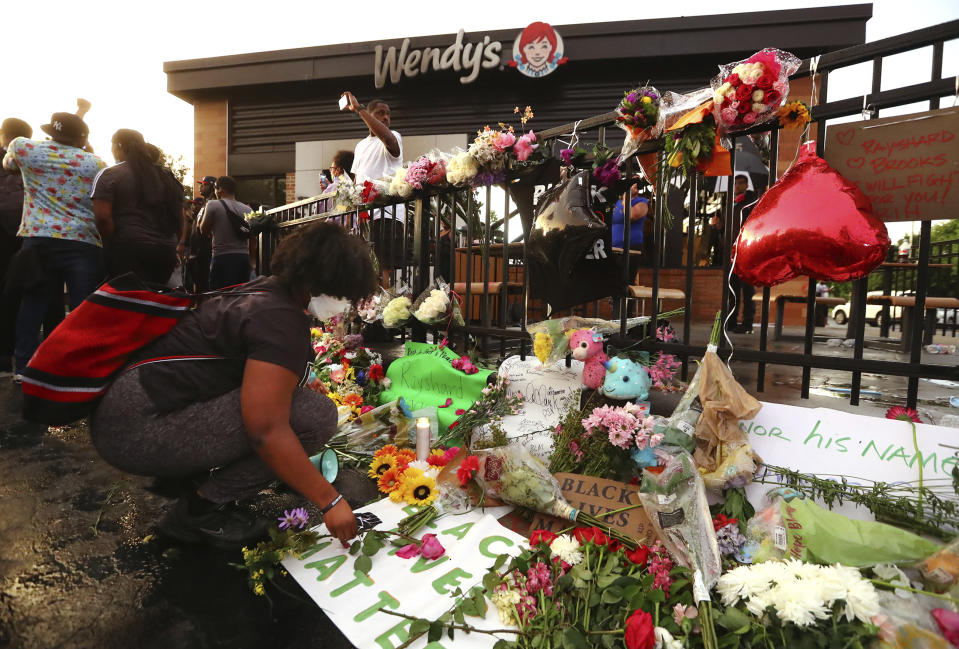 Tayla Myree sets out flowers on a shrine at a burned Wendy's on Sunday, June 14, 2020, in Atlanta. Rayshard Brooks, a 27-year-old black man, was fatally shot by a white Atlanta police officer outside the Wendy's on Friday night. (Curtis Compton/Atlanta Journal-Constitution via AP)