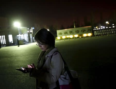 Women's rights activist Feng Yuan uses her mobile phone as she waits for the release of detained women activists in front of a detention center in Beijing, April 13, 2015. REUTERS/Kim Kyung-Hoon