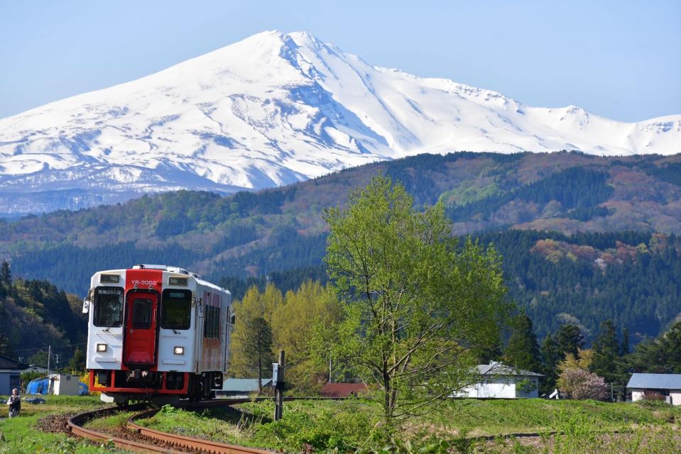  襯托在由利高原鐵道單節列車後方的，是白雪皚皚的鳥海山。