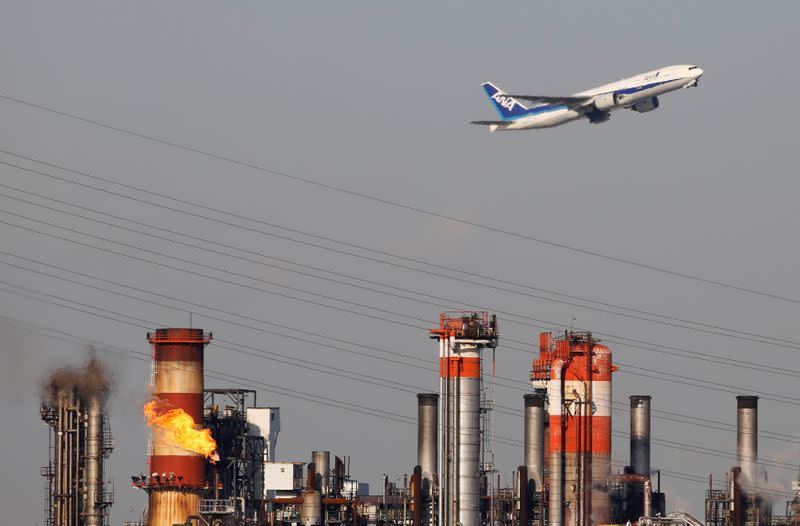 FILE PHOTO: FILE PHOTO: An All Nippon Airways' plane flies over a chimney of an oil refinery in Kawasaki