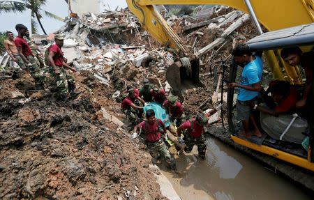 Members of the military carry a dead victim during a rescue mission after a garbage dump collapsed and buried dozens of houses in Colombo, Sri Lanka April 15, 2017. REUTERS/Dinuka Liyanawatte