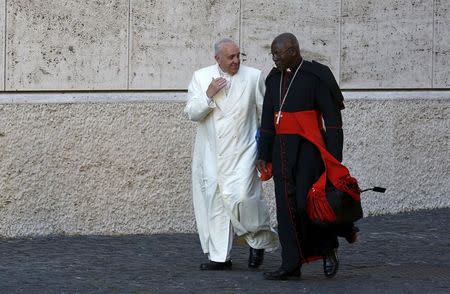 Pope Francis chats with Cardinal Philippe Nakellentuba Ouedraogo (R) as he arrives to lead the synod on the family in the Synod hall at the Vatican, October 23, 2015.REUTERS/Alessandro Bianchi