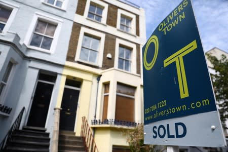 An estate agent board is displayed outside a property in London